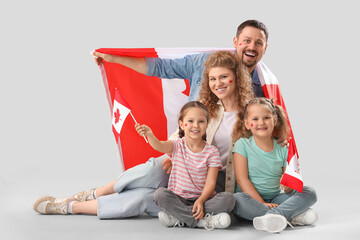 Wall Mural - Happy beautiful family with flags of Canada sitting on grey background