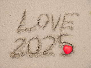 Wall Mural - Sign love and 2025 on beach sand and red heart. Hand made message.