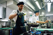© Drazen - Restaurant chef preparing food in frying pan in kitchen.