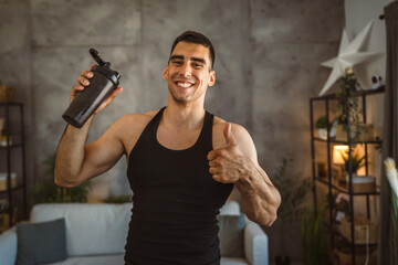 Portrait of young man stand and hold shaker in the living room