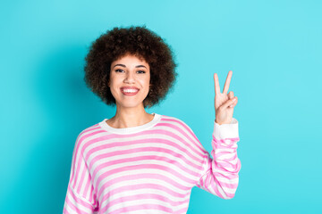 Photo of adorable lovely girl wear striped sweater showing v-sign empty space isolated blue color background