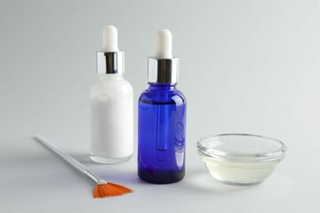 Poster - Bottles of chemical peel, bowl with liquid and brush on light background, closeup. Peeling procedure