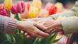 © sungedi - Little daughter hugging her mother and gives her a bouquet of flowers tulips at park. Happy Mother's day concept. copy space for text.