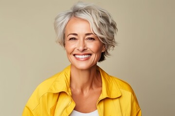 Poster - Portrait of a happy senior woman in yellow jacket over grey background