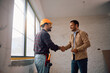 © Drazen - Happy man shaking hands with construction site worker at his renovating home.