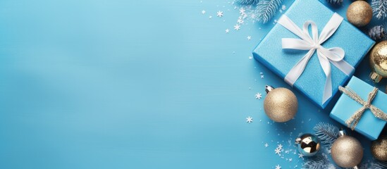 Wall Mural - Festive Christmas scene featuring a blue background adorned with gift box and decorations in a flat lay style, with ample copy space image.