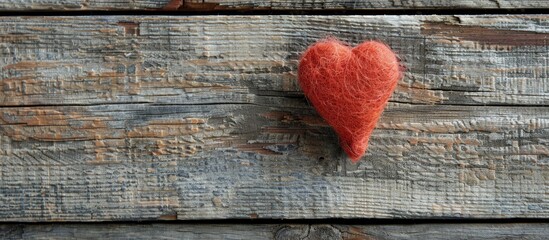 Wall Mural - A heart-shaped piece of felt displayed on a rustic wooden surface with ample space for text or additional graphic elements in the picture.