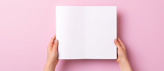 Poster - High-quality photo of a person holding a book mockup against a pink background with an empty white hardcover for text or design, providing ample copy space image.
