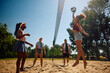© Drazen - Group of friends playing volleyball on the beach.