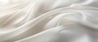 © vxnaghiyev - Close-up of a light, flowing fabric creating a soft and elegant background with ample copy space image on a white or light ivory backdrop.