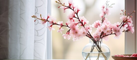 Poster - Close-up of pink blooming branches in a glass vase in front of a window with copy space image.