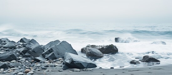 Poster - Seaside scene with gray rocks amidst the sea and white foamy waves along the shore creating a tranquil ambiance for a copy space image.