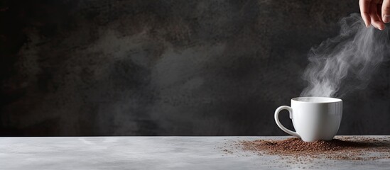 A woman pours instant coffee into a white mug on a grey stone table, with available copy space for adding text or images.