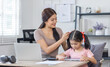 © David - Asian business lady working on computer while her daughter hugging her