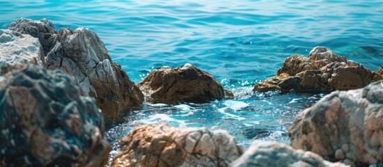 Wall Mural - Close-up view of a rocky shore by the clear blue ocean with a background setting, suitable for text. Copy space image. Place for adding text and design
