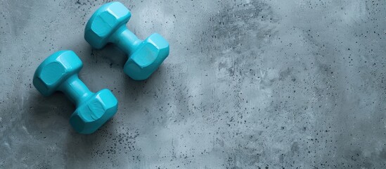Aufkleber - Cyan blue plastic dumbbells on a grey textured background for a fitness concept, with a pair of small barbells providing a copy space image from a top view.
