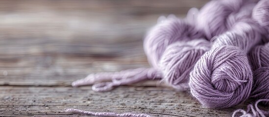 Poster - Engaging in knitting as a hobby with a background of a skein of pale lilac wool thread on a wooden table creates a serene and inviting atmosphere for a copy space image.