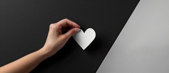 Aufkleber - Adult hand reaching for a heart-shaped paper cutout against a black and white abstract background, perfect for creating a card or invitation banner with copy space image.