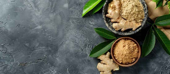 Wall Mural - Ginger powder, fresh root, and leaves displayed on a grey table in a flat lay composition, providing room for text in the image. Copy space image. Place for adding text and design