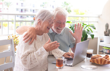 Poster - Video call concept. Happy bonding senior couple have breakfast on home terrace using laptop technology for online webcam connection, enjoying carefree moments together with distant family