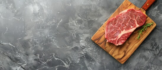 Poster - Top view image of marbled raw pork steak on a cutting board against a gray backdrop, with room for text or additional elements.