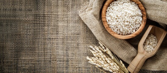 Poster - A top-view image with copy space featuring a wooden scoop and bowl filled with rice cereal on a textured sackcloth surface.