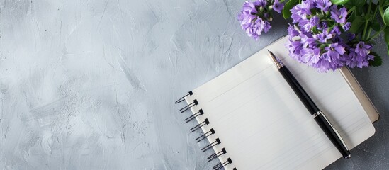 Leinwandbilder - Flat lay with a notebook, a pen, and a purple flower arranged on a gray backdrop, seen from a top view, creating a composition with copy space image.