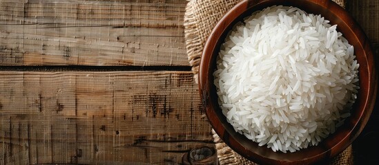 Poster - High-resolution top-view close-up of white rice in a wooden bowl with abundant copy space image.