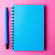 © Nasreen - A blue notebook in the top left corner of a solid pink background, ready for taking notes.