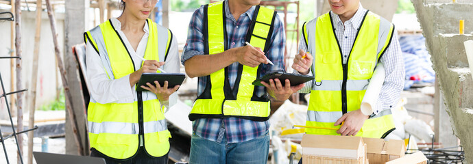 Wall Mural - Engineer teams meeting working together wear worker helmets hardhat on construction site in city.