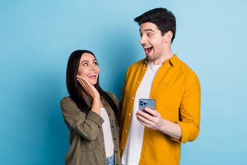 Poster - Portrait of two young people hold smart phone wear shirt isolated on blue color background