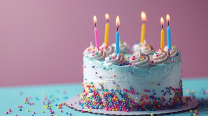 Birthday cake with lit candles on a blue table, decorated with sprinkles. Festive birthday celebration concept with delicious vanilla cake and pastel colors.