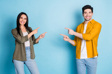 Poster - Photo of two nice young partners direct fingers empty space wear shirt isolated on blue color background