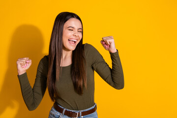 Poster - Photo portrait of attractive teen woman raise fists winning dressed stylish khaki clothes isolated on yellow color background