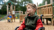 © fotogurme - A child with a mobility aid watching other children play on inaccessible playground equipment