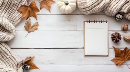 Poster - A white notebook sits on a wooden table with autumn leaves and pumpkins. The notebook is empty, but the scene evokes a sense of warmth and coziness, as if someone is about to write down their thoughts