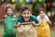 © Paniti - students participating in sack race, laughing and having fun, [fun activities], [sports day]