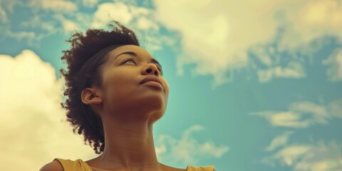 Wall Mural - A woman with a short, curly hairstyle is looking up at the sky