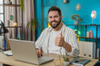© Andrii Iemelianenko - Like. Smiling young Caucasian business man looking approvingly at camera showing double thumbs up sign positive something good great news positive feedback. Happy guy at home office desk. Lifestyle