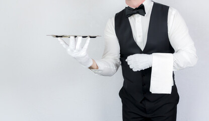 Wall Mural - Classic Butler or Waiter in Black Waistcoat or Vest and Bowtie Holding Serving Tray. White Glove Service and Professional Hospitality.