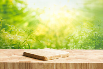 Wall Mural - Selective focus.End grain wood counter top with cutting board on blur greeny flower garden in morning with nature light