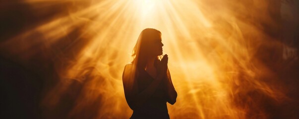 Wall Mural - Silhouette of a woman praying under a dramatic sky, bathed in warm light