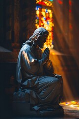 Wall Mural - Light shining through stained glass illuminates a statue of jesus christ in a church