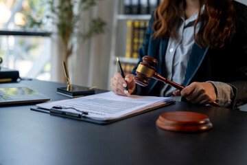 A woman in a suit is writing on a piece of paper with a gavel in her hand