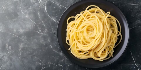 Wall Mural - Top view of Cacio e Pepe spaghetti on dark marble table. Concept Food Photography, Italian Cuisine, Pasta Recipe, Dark Marble Background, Traditional Dish