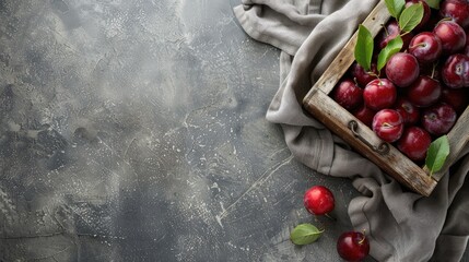 Wall Mural - Organic plums in wooden box with gray fabric space for text Flat lay