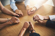 © peopleimages.com - Praying, holding hands and group with religion, table and belief in God, Christian and faith in holy spirit. Support, solidarity or together to worship, praise and trust in Christ or people in church