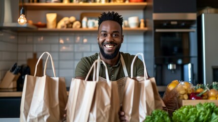 Wall Mural - Smiling man with paper bags of groceries at kitchen.