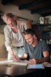 © DoneDeal/peopleimages.com - Senior man, architecture blueprint and student with learning for education, knowledge and study in home. Architect, elderly dad and son with floor plan for family business, entrepreneur and design