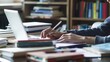 © farhan - young professional using a laptop to write a research paper, surrounded by books and notes in a quiet study space